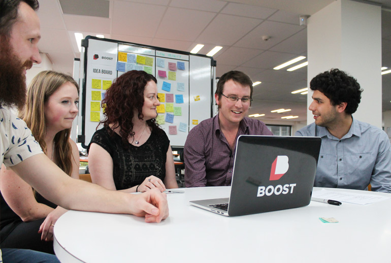 A Product Owner and stakeholders sit at a table with a laptop preparing for an upcoming Sprint Planning meeting.