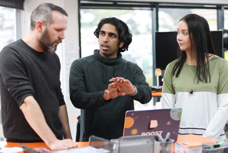 Three Scrum Team members discuss user stories at a laptop. 