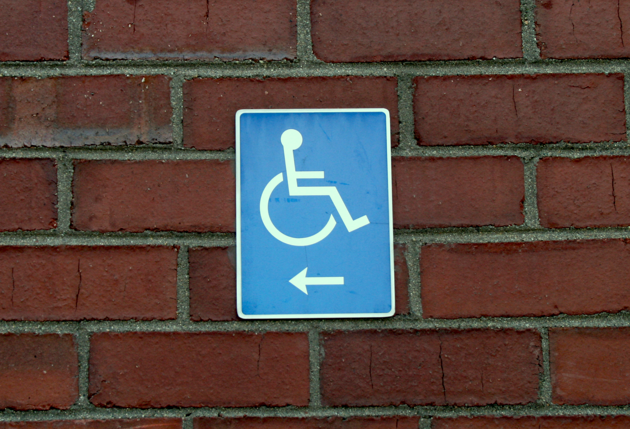 International Symbol of Access sign with arrow on brick wall. Get a pathway to website accessibility.